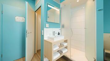 Ein Badezimmer mit Dusche, Waschbecken und Spiegel.