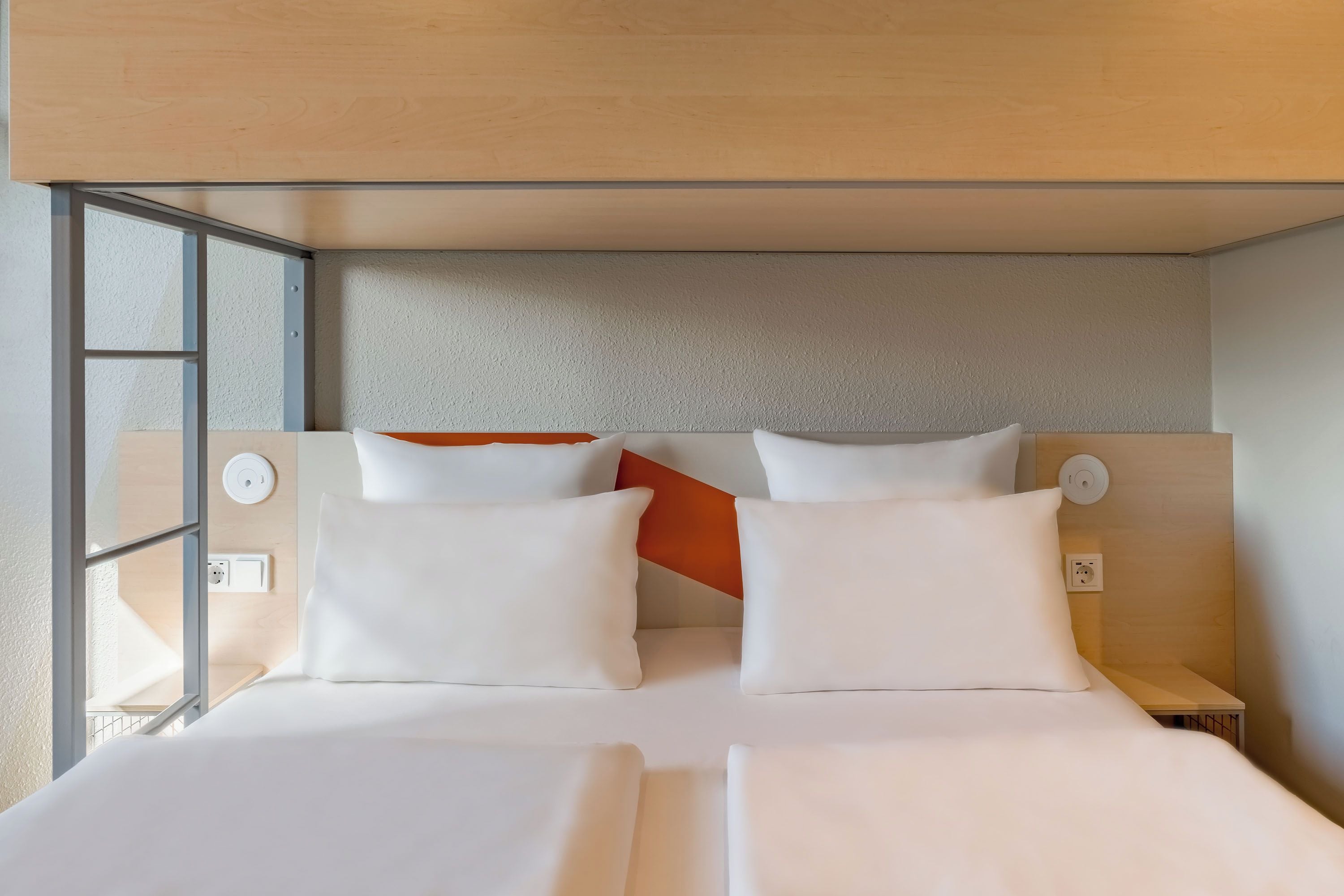 Een moderne hotelkamer met een groot bed, twee kussens, een nachtkastje en een raam met uitzicht.