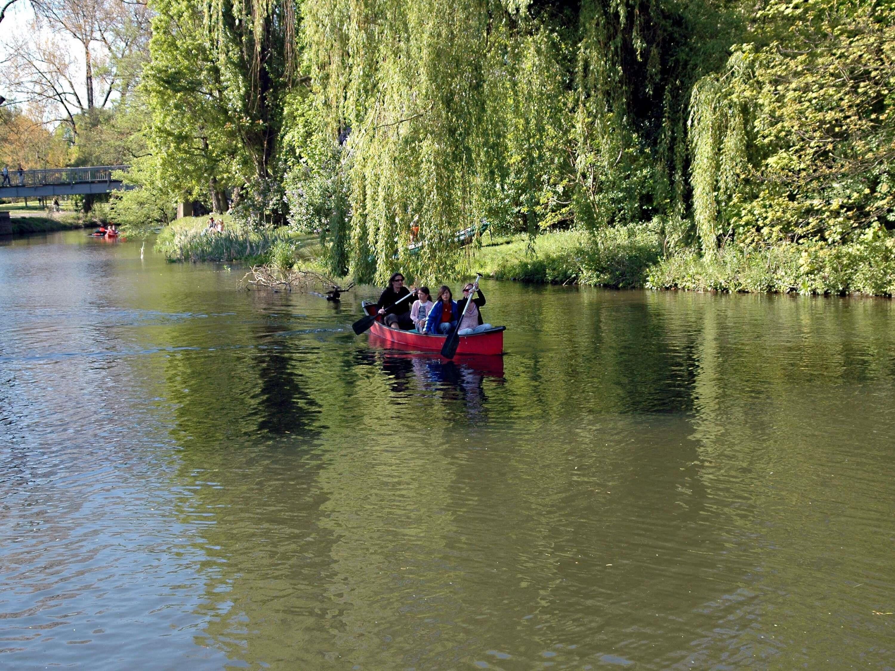 Un grupo de personas en una embarcación roja en un río tranquilo, rodeado de exuberante vegetación y árboles.