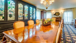 A dining room with a large wooden table, chairs, a chandelier, and a cabinet with glass doors displaying various items. - Azalea Plantation B&B (Fort Worth)