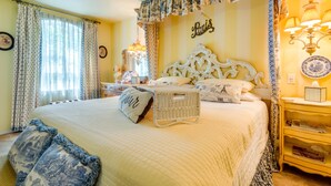 A bedroom with a large bed, a bedside table, a lamp, and a wall clock. - Azalea Plantation B&B (Fort Worth)