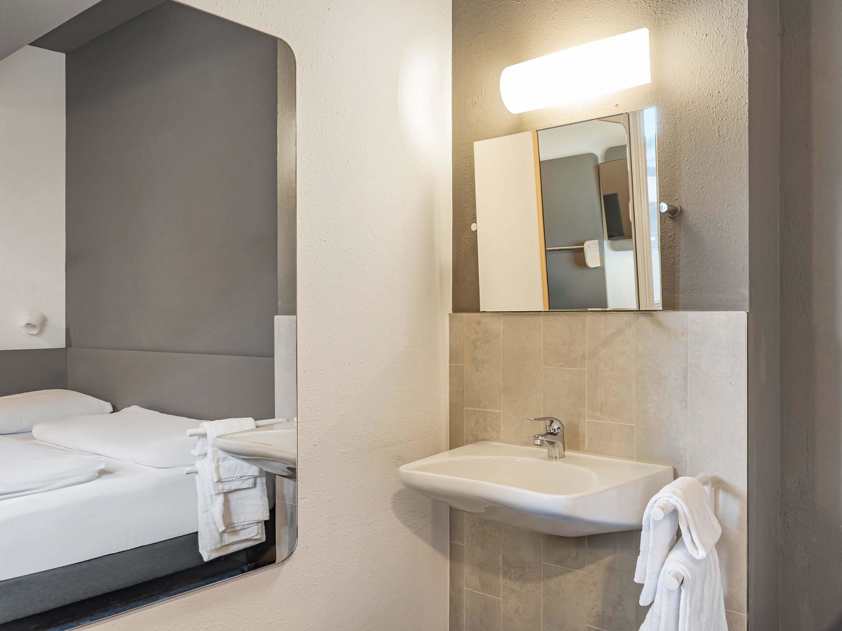 Ein modernes Badezimmer mit großem Spiegel, Waschbecken und Toilette.