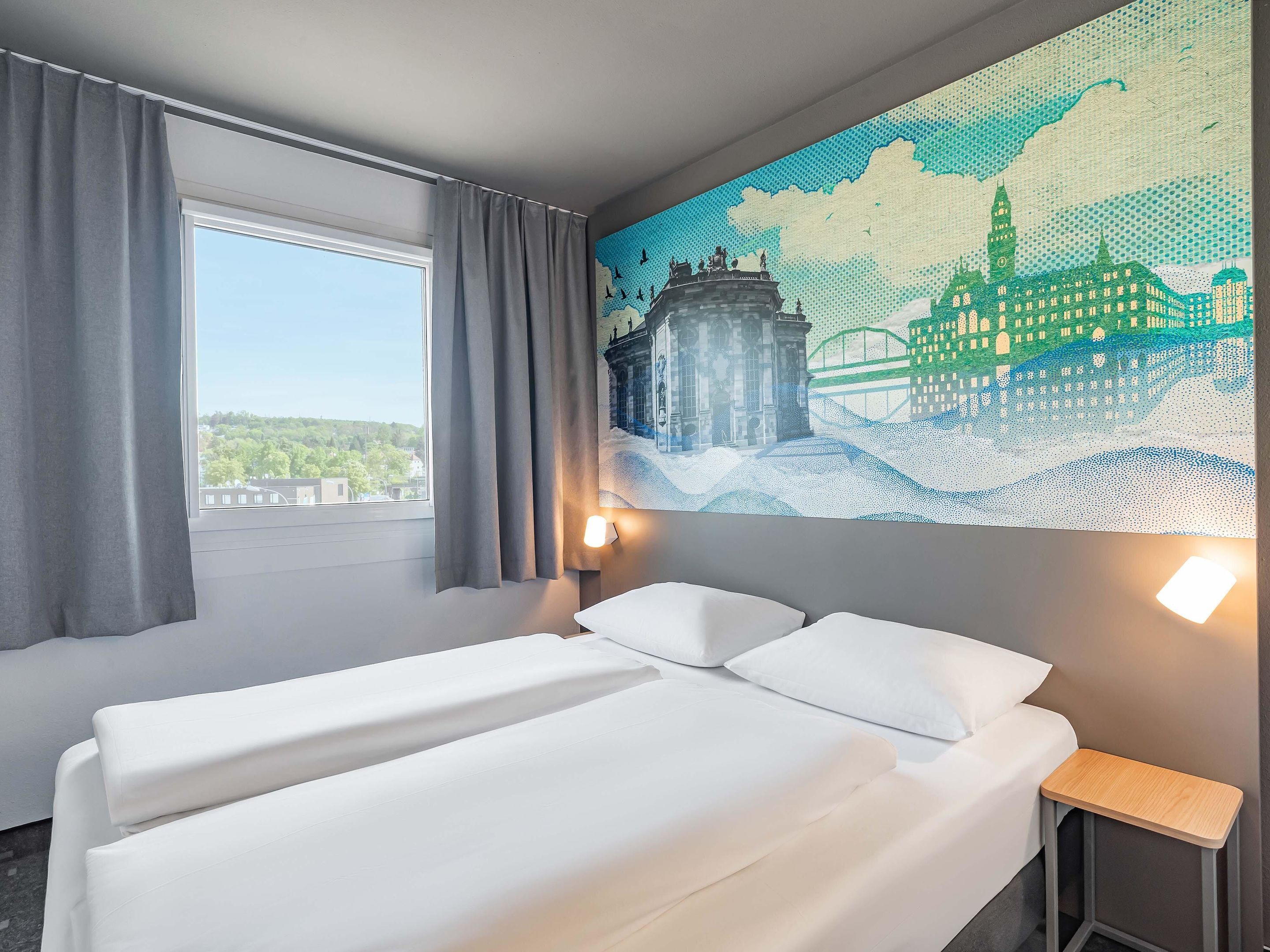 Ein Hotelzimmer mit Bett, einem Vorhangfenster, einer Wandlampe und einem großen Mosaikbild.