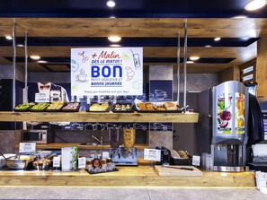 Een ontbijtbuffet met diverse gerechten en een koffieapparaat.