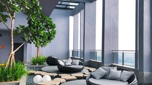 A modern outdoor lounge area with a circular seating arrangement, a small water feature, and a view of the city through large windows. - Expressionz Professional Suites by Luxurious Lifestyle Living (Kuala Lumpur)