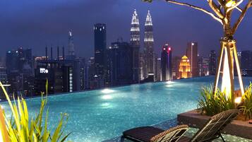 A nighttime pool area with a city skyline in the background, including the Petronas Towers.