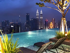 Zona de piscina nocturna con un horizonte urbano de fondo, incluyendo las Torres Petronas.