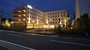 A multi-story hotel with a modern design, featuring a parking area in front.
