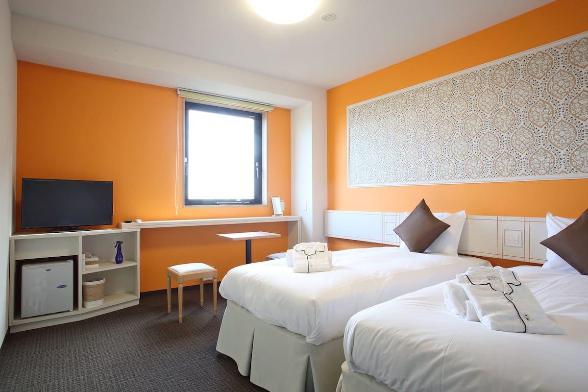 Een hotelkamer met twee bedden, een televisie, een bureau en een raam.