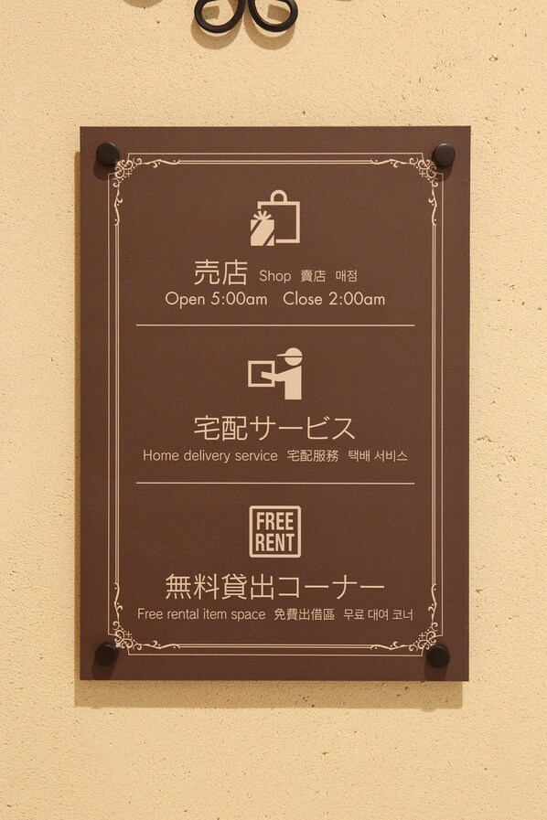 A brown sign with white text and icons, detailing store hours, home delivery service, and free rental item space. - Hotel Eurasia Maihama Annex (Urayasu)