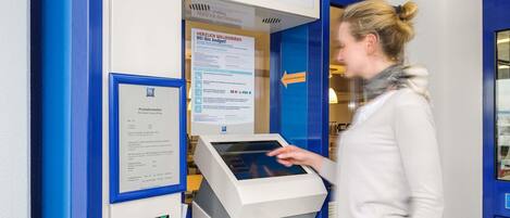 A check-in point with a digital kiosk and a ticket machine.