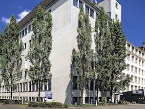 Ein modernes Hotelgebäude mit mehreren Etagen, großen Fenstern und einem Schild mit der Aufschrift 'ibis budget hotel'.