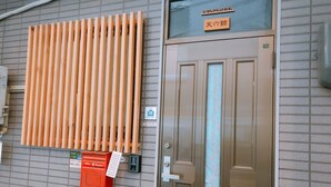 A hotel entrance with a wooden slat design, a signboard with Japanese characters, and a red mailbox.