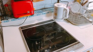 A kitchen with a Mitsubishi induction cooktop, a red toaster, and a white coffee maker.