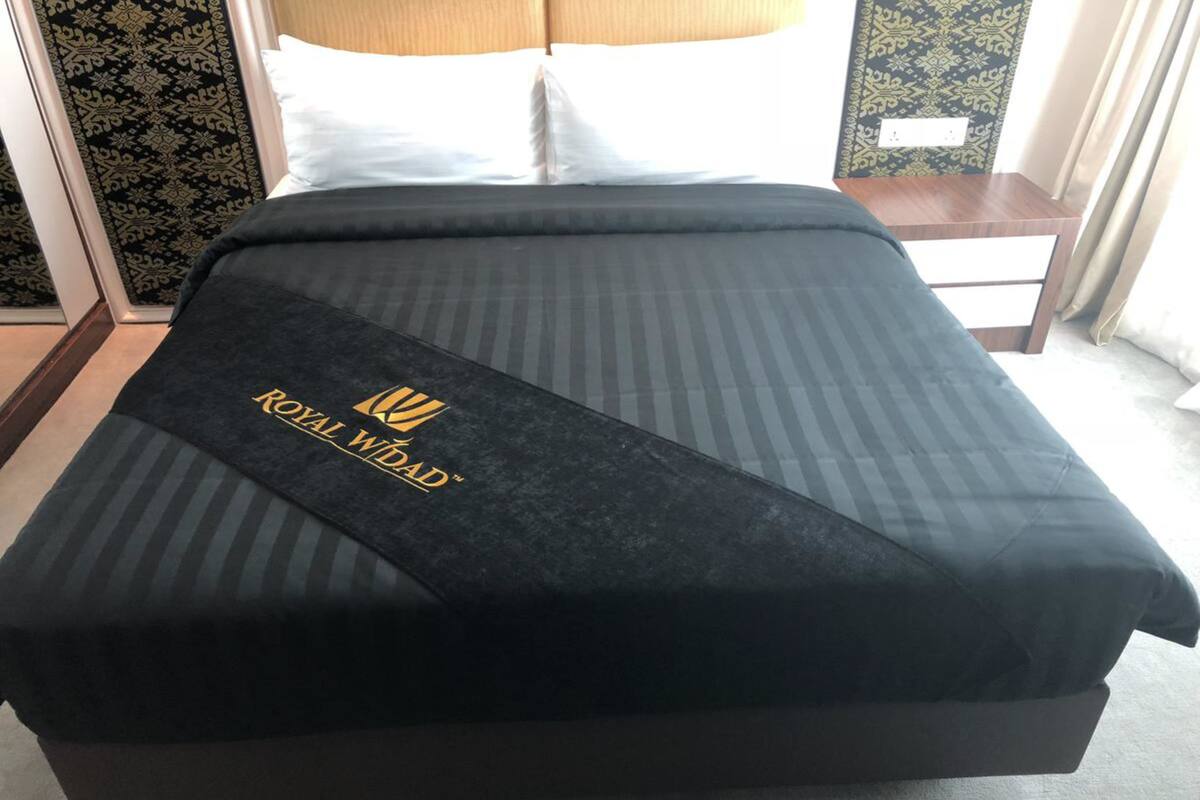 A hotel room with a bed, a nightstand, and a patterned wall.