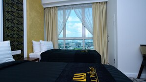Una habitación de hotel con una cama grande, vistas de la ciudad a través de una ventana y un papel tapiz estampado.