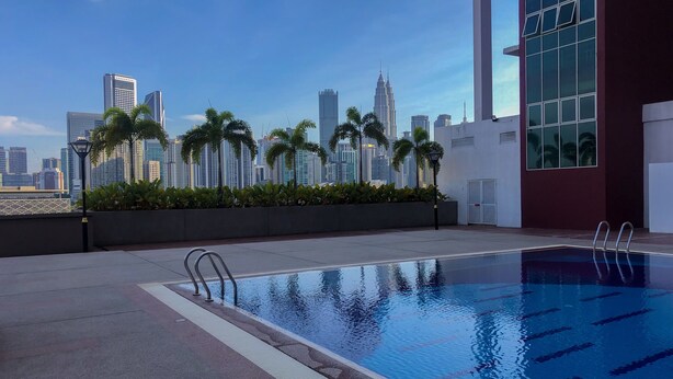 Una piscina en la azotea con vistas al horizonte urbano, que incluye edificios altos y palmeras.
