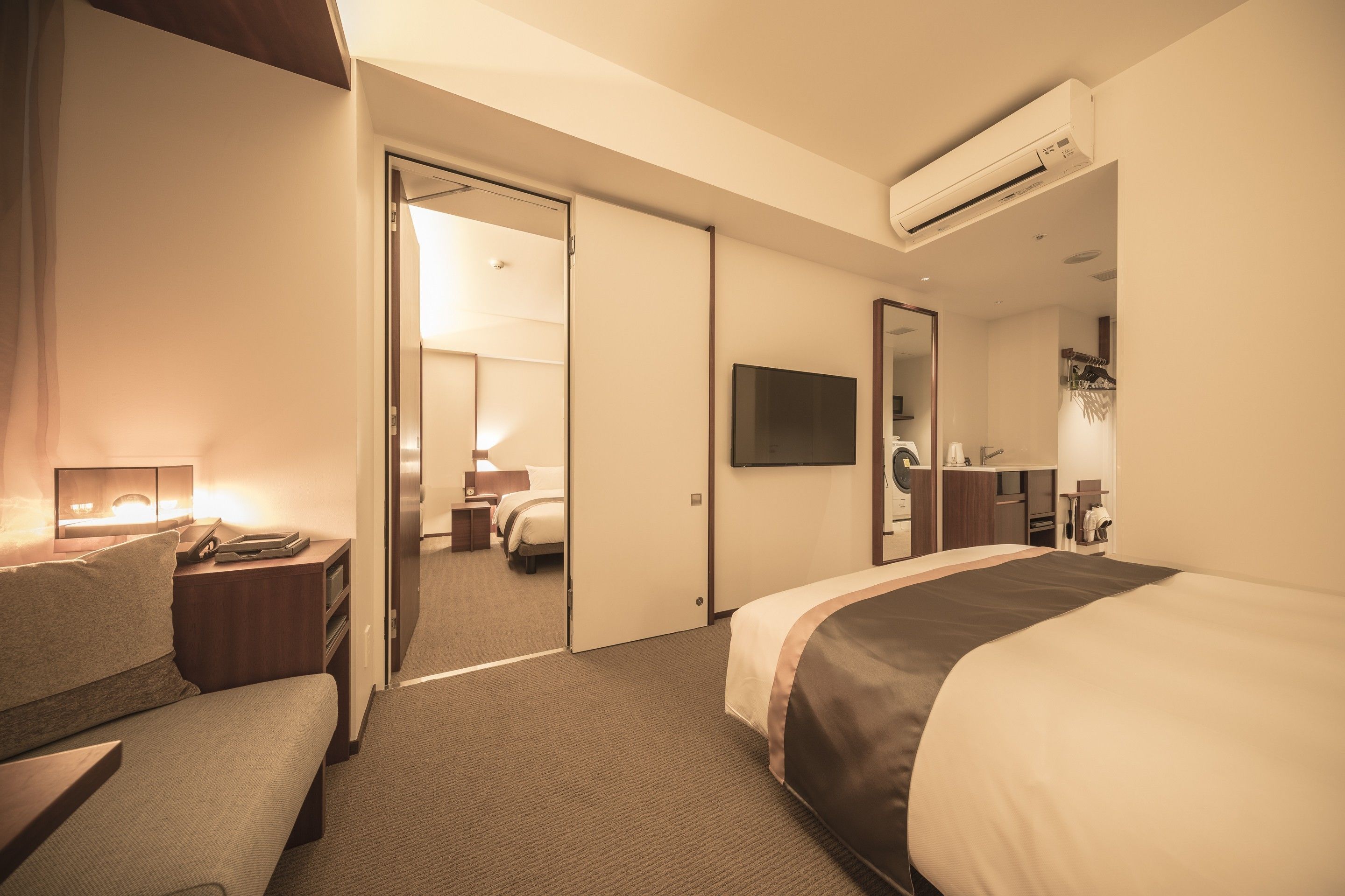 Habitación de hotel con cama, escritorio, silla, televisión y baño visible a través de una puerta abierta.