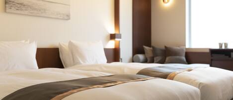 A hotel room with two beds, a nightstand, a lamp, and a window.