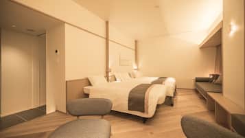 Una habitación de hotel moderna con una cama grande, dos sillones, un sofá y un escritorio.