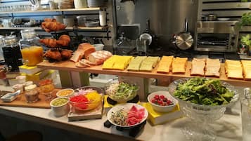A buffet with various food items including bread, pastries, and salads.