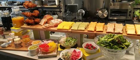 A buffet with various food items including bread, pastries, and salads.