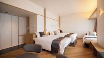Una habitación de hotel moderna con una cama grande, dos camas más pequeñas, un área de descanso y un armario.