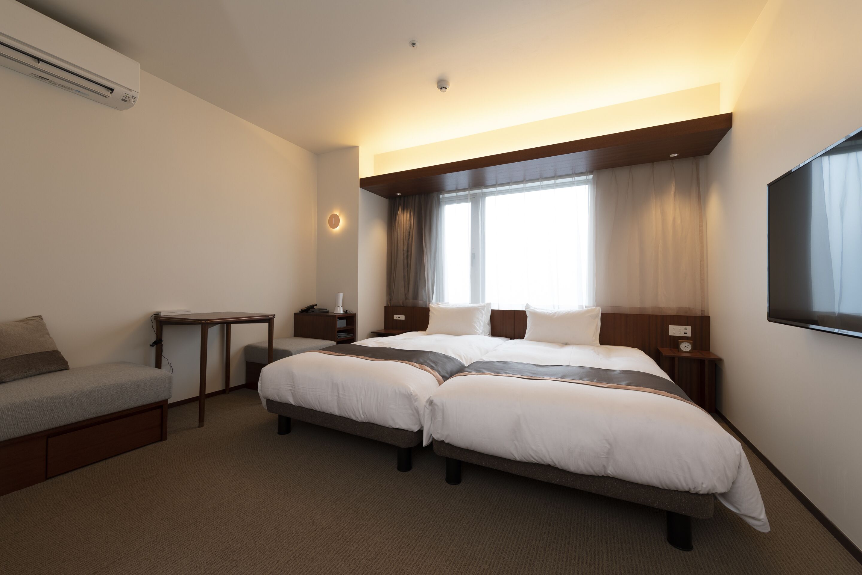 Ein Hotelzimmer mit einem großen Bett, einem Schreibtisch, einem Stuhl und einem Fernseher.