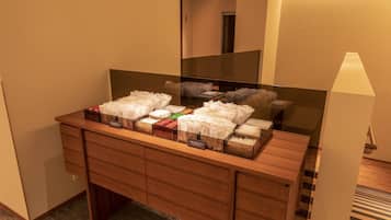 A hotel bathroom with a wooden vanity, a mirror, and a variety of toiletries in transparent containers.