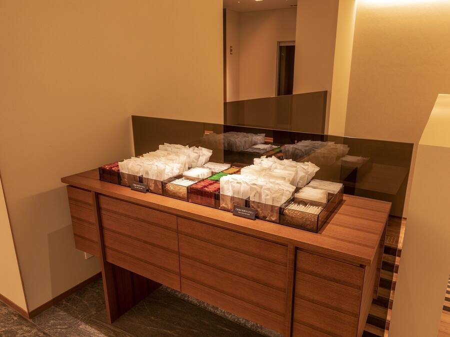 A hotel bathroom with a wooden vanity, a mirror, and a variety of toiletries in transparent containers.