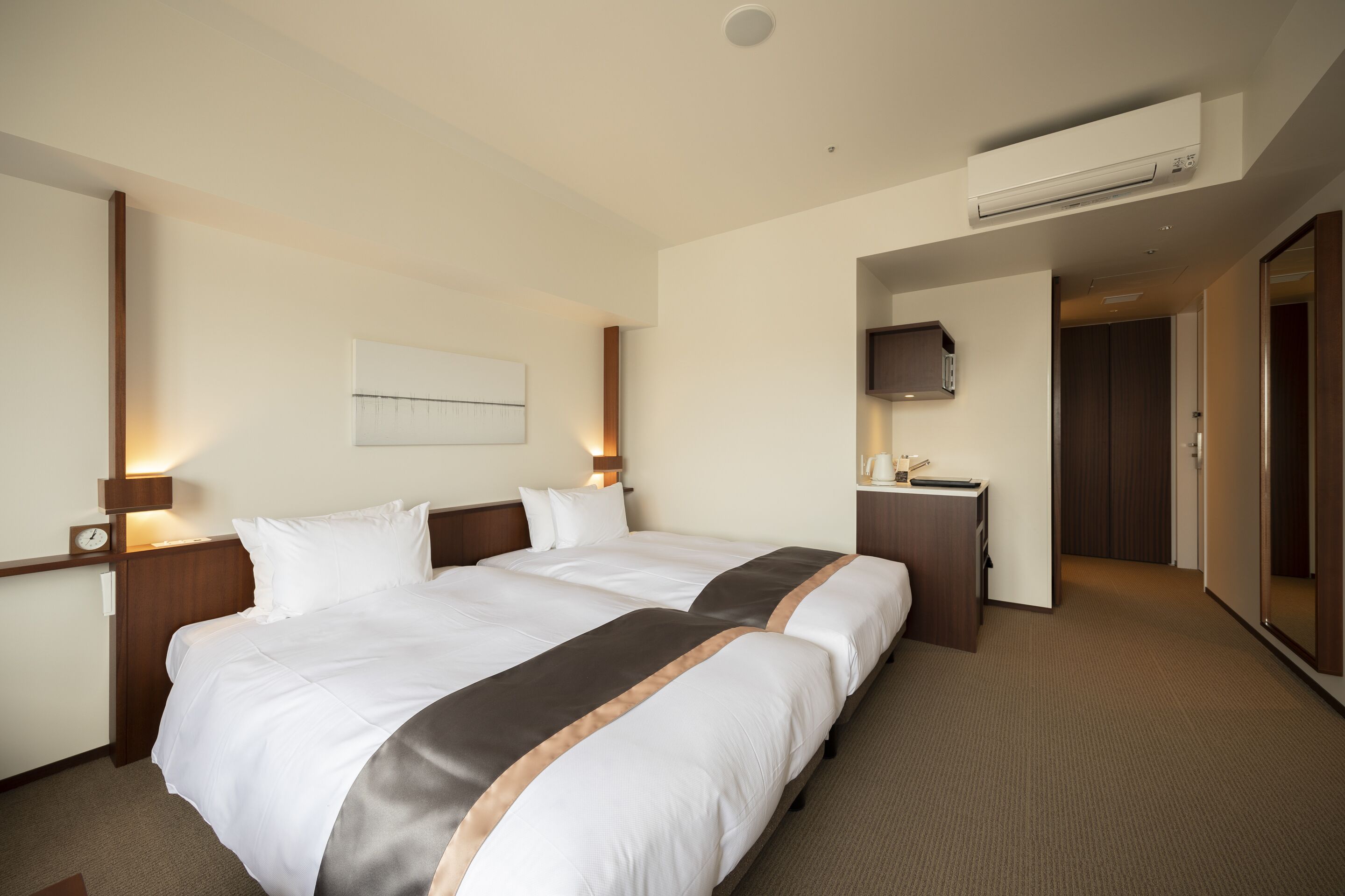 Une chambre d’hôtel avec deux lits, un bureau, une télévision et un appareil de climatisation.