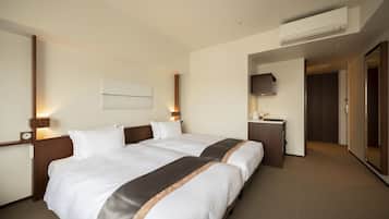 Quarto de hotel com duas camas, uma escrivaninha, uma televisão e um ar condicionado.