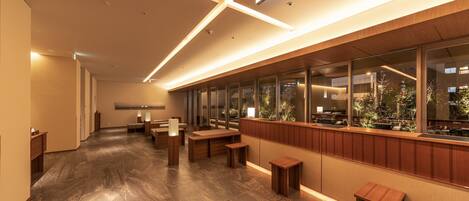 A modern interior with a long corridor, wooden benches, and a view through large windows.