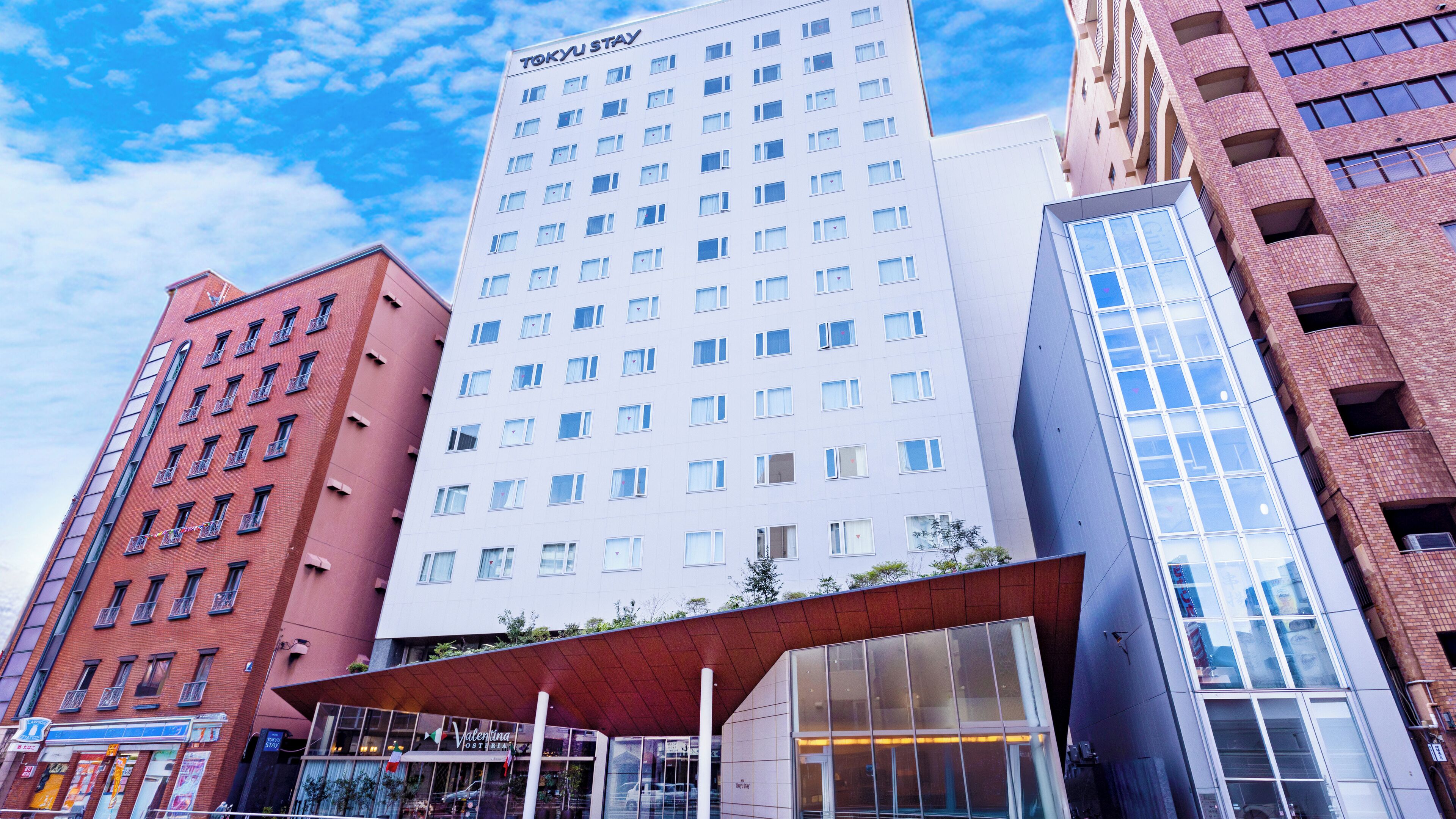 A modern hotel with multiple floors, a prominent 'TOKYU STAY' sign, and a variety of window styles.
