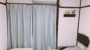 Una habitación con una cama, una mesita de noche, un televisor montado en la pared y aire acondicionado.