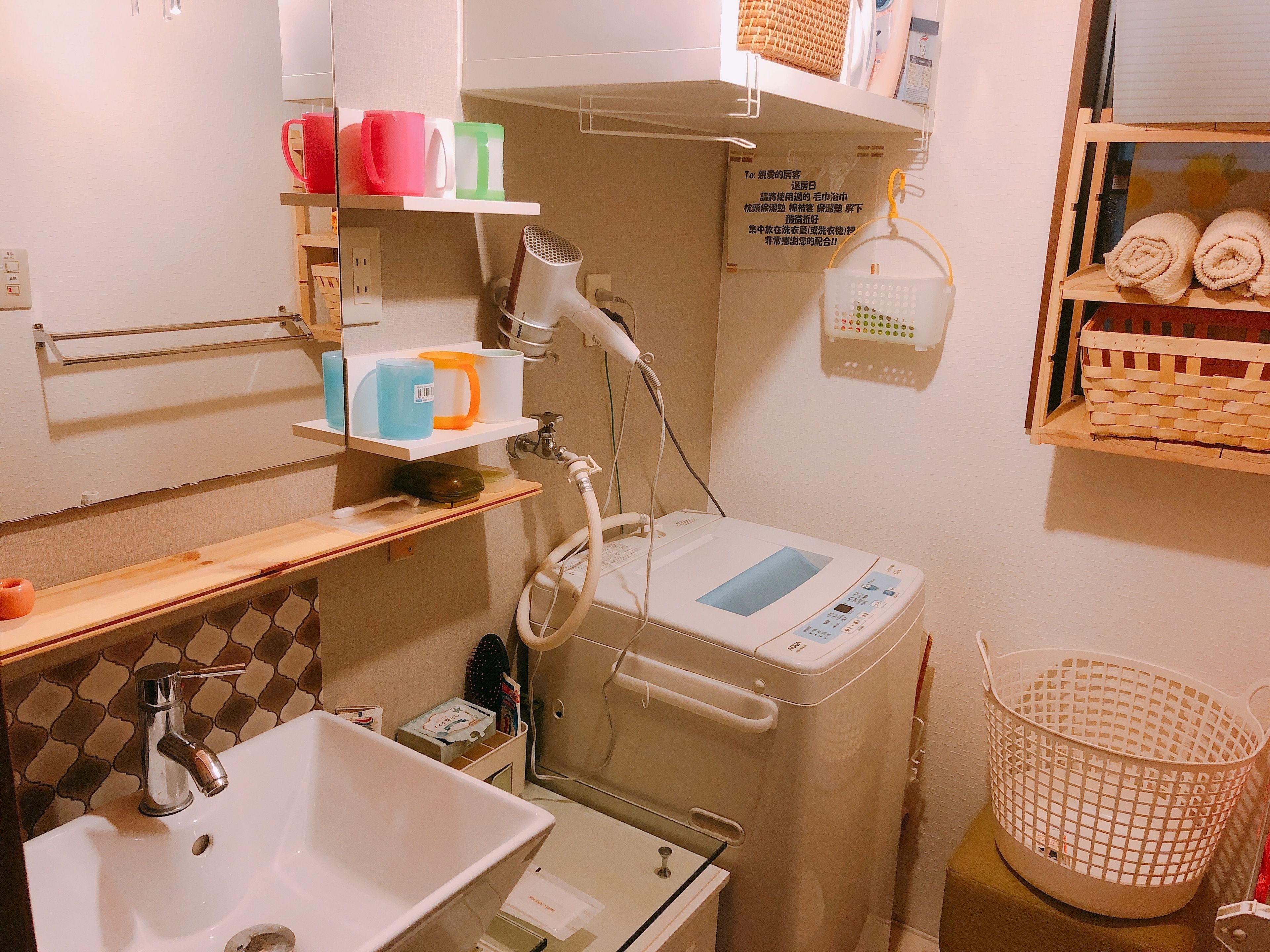 A compact bathroom with a sink, a hairdryer, and a small shelf with toiletries.