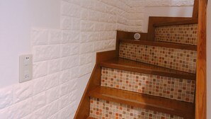 Una escalera con paredes de textura blanca y peldaños de madera.