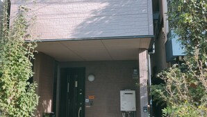 Un edificio residencial con fachada de ladrillo, una puerta de entrada oscura y un pequeño porche.