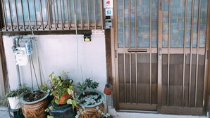 A hotel entrance with a gated door, a PayPay payment terminal, and several potted plants. - Ryokoheya Tenchokan (Osaka)