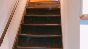 A wooden staircase with a handrail, leading to a room with a wooden door. - Ryokoheya Tenchokan (Osaka)