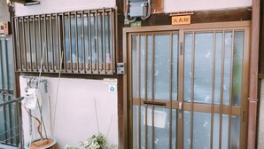 A traditional Japanese gate with a wooden sign above it. - Ryokoheya Tenchokan (Osaka)