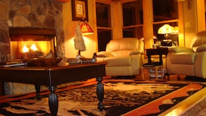 A cozy living room with a fireplace, leather chairs, a coffee table, and a patterned rug. - HEAVEN'S PEAK - Luxurious, mountain top retreat; 5 Star  (Ranger)