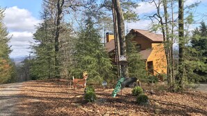 A cabin surrounded by trees, with a deer sculpture and a peacock sculpture in the yard. - HEAVEN'S PEAK - Luxurious, mountain top retreat; 5 Star  (Ranger)