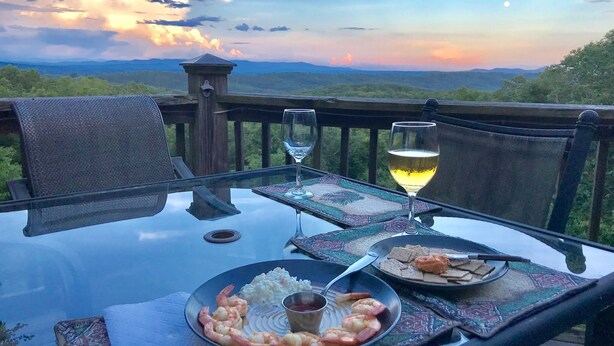 A table with a glass of white wine, a plate of shrimp, and a bowl of rice on a balcony overlooking a mountainous landscape during sunset. - HEAVEN'S PEAK - Luxurious, mountain top retreat; 5 Star  (Ranger)