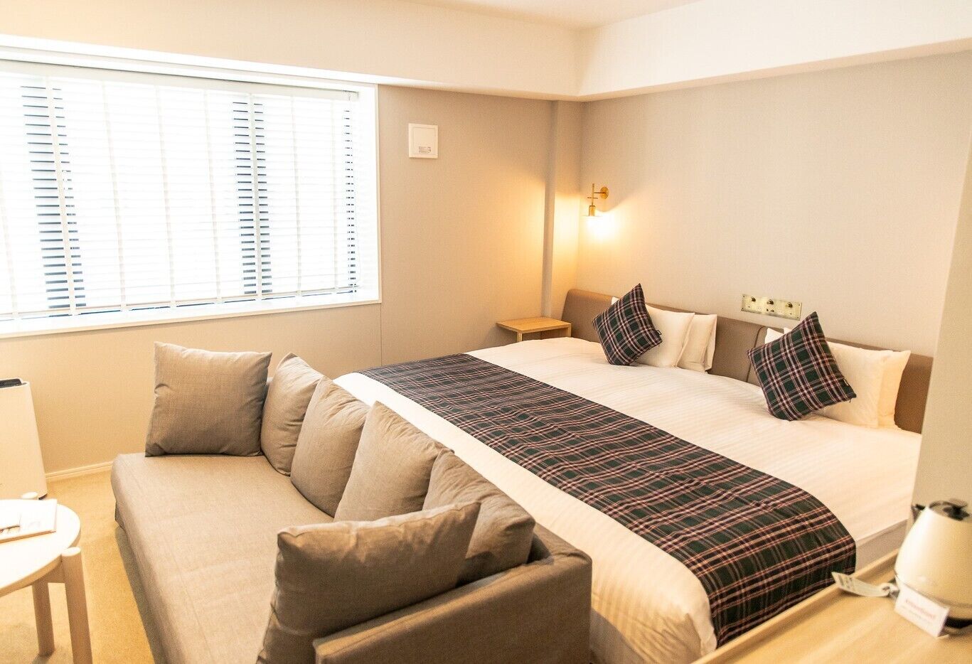 Una habitación de hotel con una cama, un sofá, una mesita de noche y una lámpara.