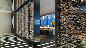 A modern interior with a glass wall displaying numerous items, a bar area, and a seating space. - Niccolo Changsha (Changsha)