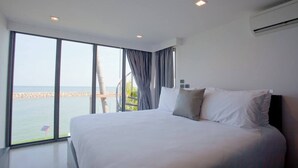 A modern hotel room with a large bed, a view of the sea, and a balcony. - Eco Moment Beach Resort Hadchaosamran (Ban Laem)