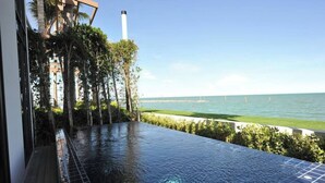 An infinity pool with a view of the ocean and a distant shoreline. - Eco Moment Beach Resort Hadchaosamran (Ban Laem)