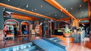 Un vestíbulo de hotel con mostrador de recepción, zona de estar y una escalera que conduce a los pisos superiores.