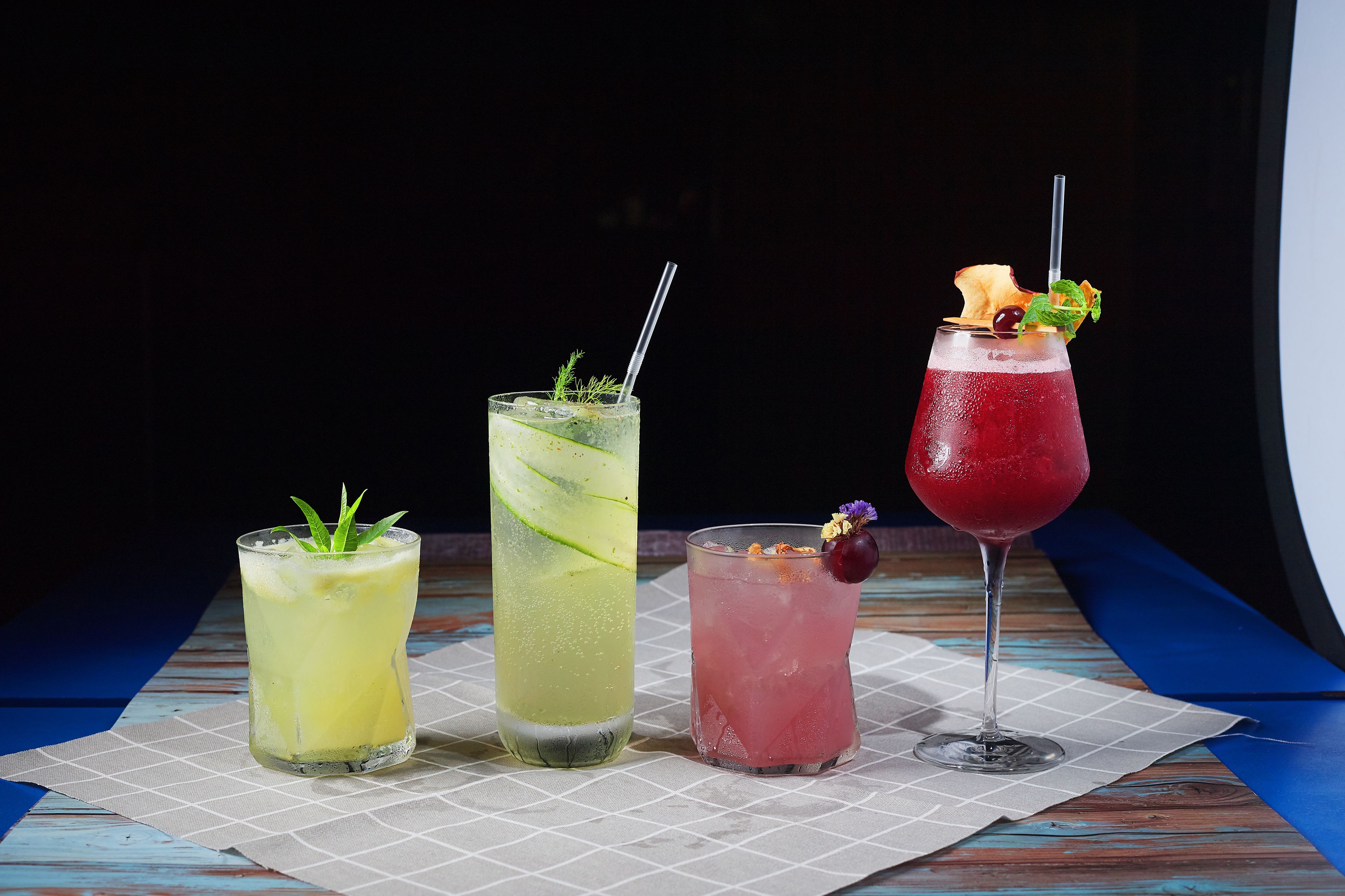 Three cocktails on a wooden table with a dark background.
